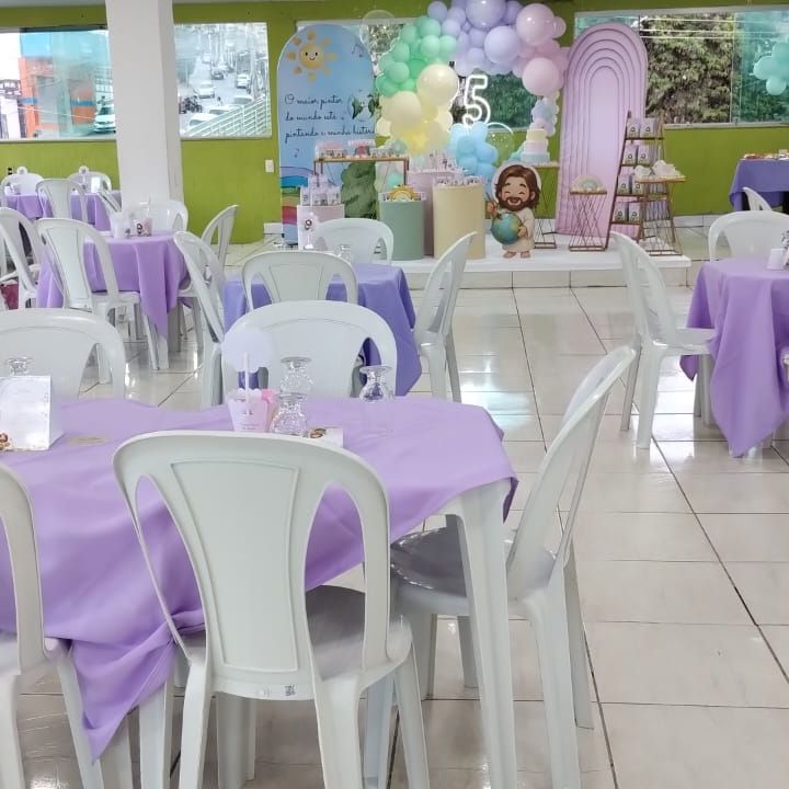 Mesas com toalhas lilás e cadeiras brancas em festa de aniversário infantil