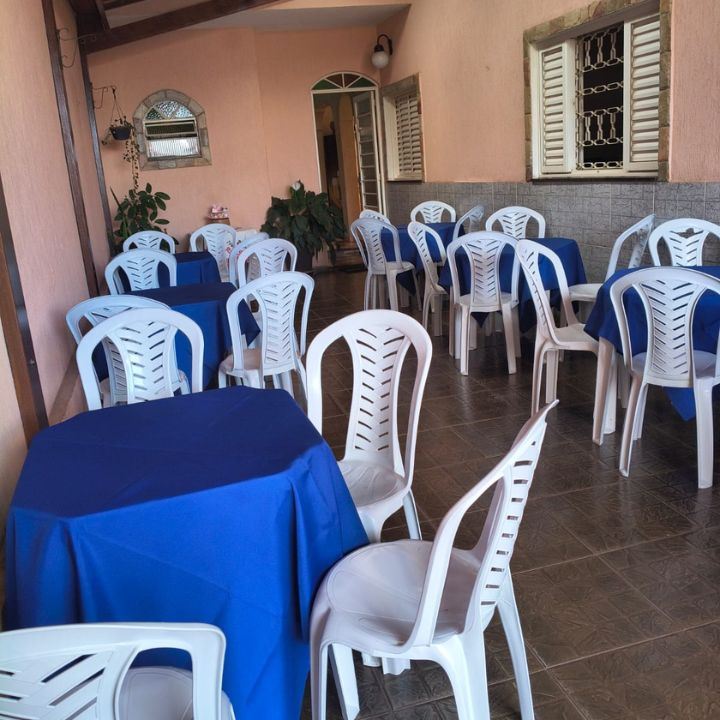Varanda com mesas de toalhas azuis e cadeiras brancas para evento
